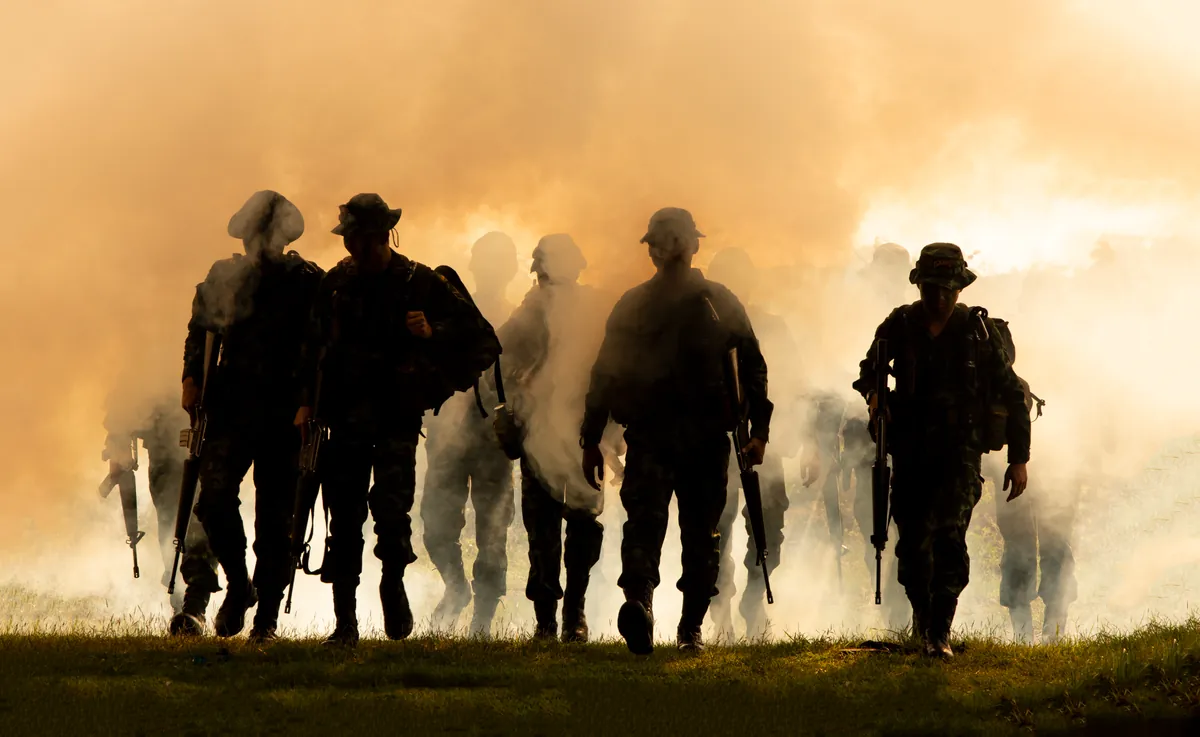Military service members walking through smoke during a training exercise, illustrating potential environmental exposures associated with Gulf War illness claims.